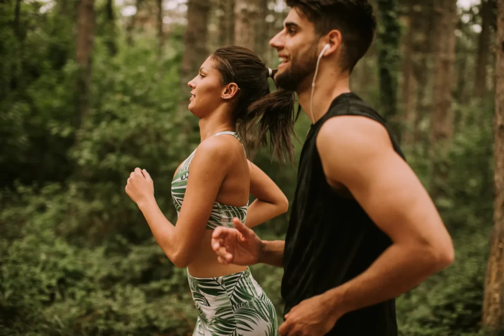 young fitness couple running at the forest trail utc